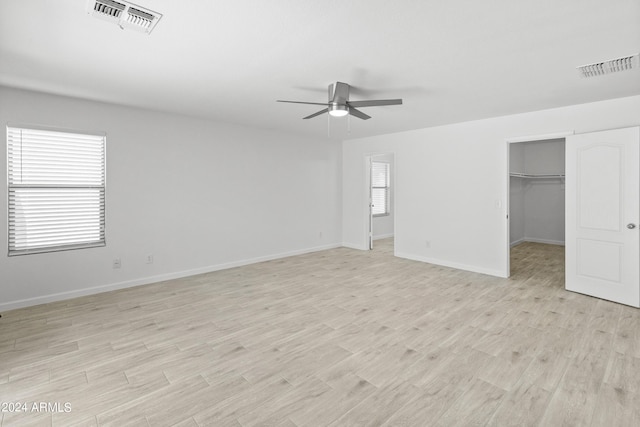 unfurnished bedroom with ceiling fan, a closet, a spacious closet, and light hardwood / wood-style floors