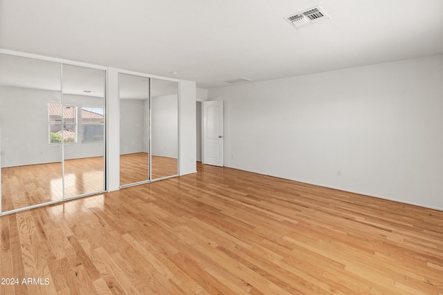 unfurnished bedroom with light hardwood / wood-style flooring and multiple closets