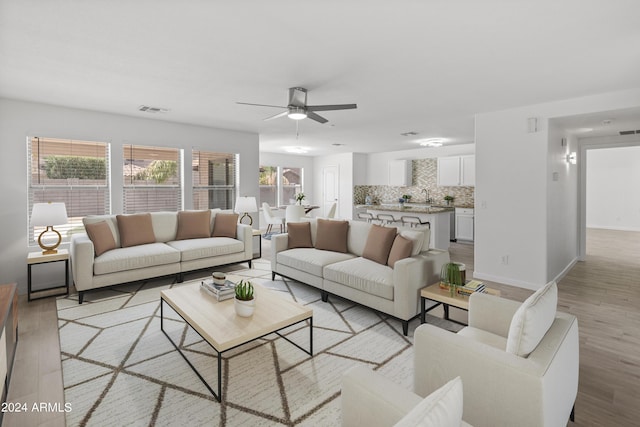 living room with light hardwood / wood-style flooring, ceiling fan, and sink