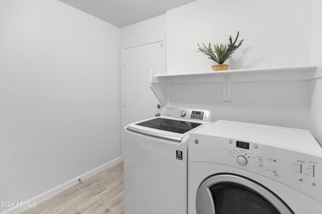 laundry area with washing machine and dryer and light hardwood / wood-style floors