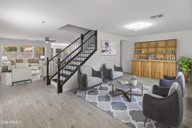 living room with ceiling fan, wood-type flooring, and bar area