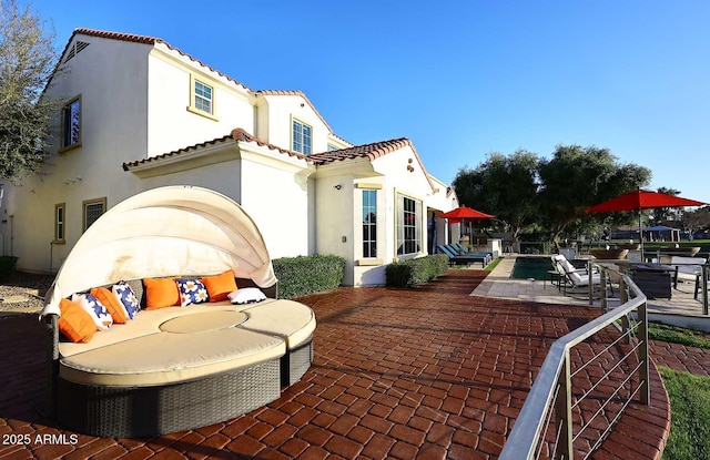 back of house featuring a patio area, a swimming pool, stucco siding, and a tile roof