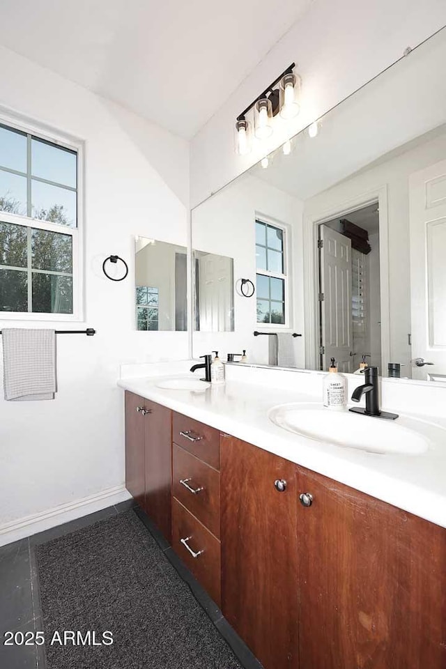 bathroom featuring double vanity, baseboards, and a sink