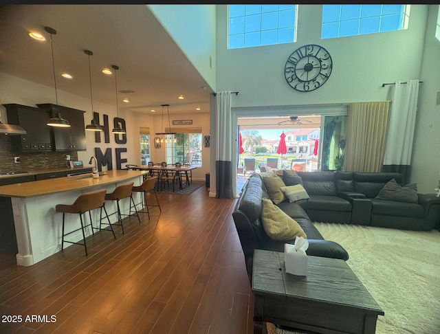 living room with recessed lighting, dark wood finished floors, and a towering ceiling