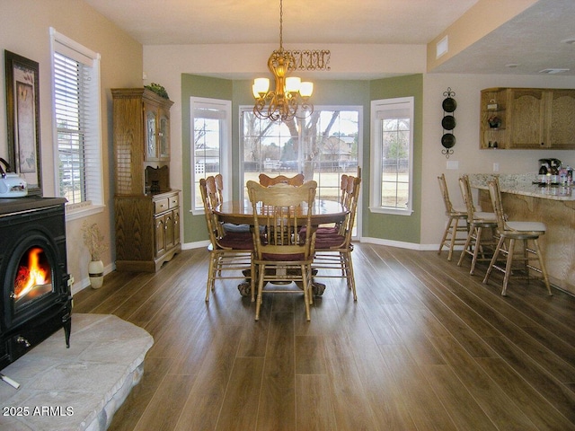 dining room featuring a notable chandelier, dark hardwood / wood-style flooring, and a wood stove