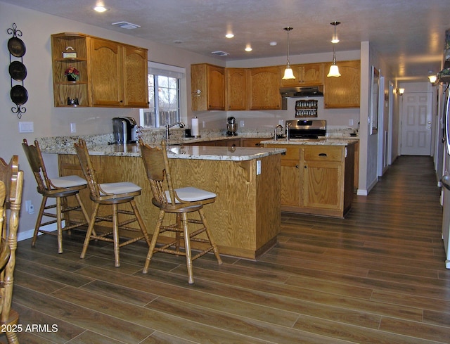 kitchen featuring hanging light fixtures, dark hardwood / wood-style floors, a kitchen breakfast bar, and kitchen peninsula