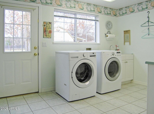 laundry area featuring cabinets, separate washer and dryer, a wealth of natural light, and light tile patterned floors