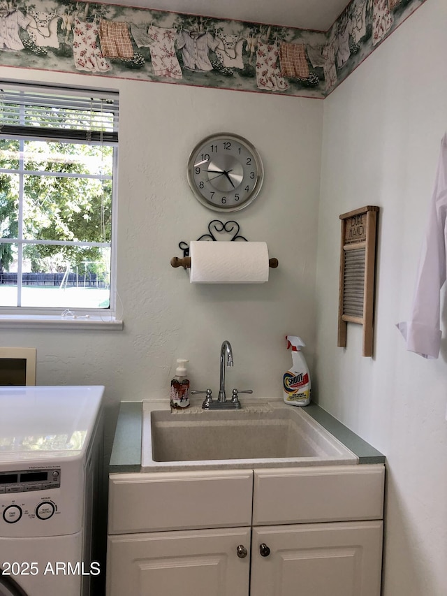 clothes washing area with cabinets, washer / dryer, and sink