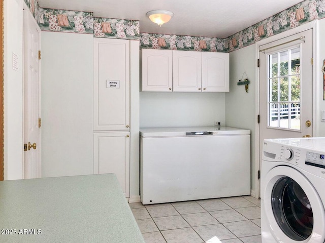 washroom featuring light tile patterned floors, washer and clothes dryer, and cabinets