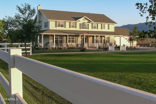 view of front facade with central AC, a porch, a mountain view, and a front lawn