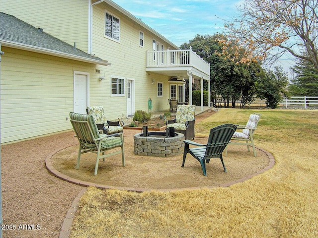 back of property with ceiling fan, a yard, a patio, an outdoor fire pit, and a balcony