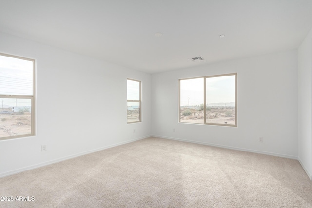 empty room featuring light colored carpet, visible vents, and baseboards