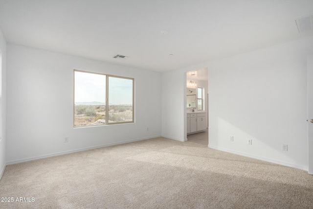 spare room featuring baseboards, visible vents, and light colored carpet