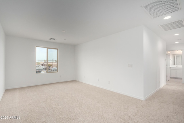 spare room featuring light carpet, baseboards, and visible vents