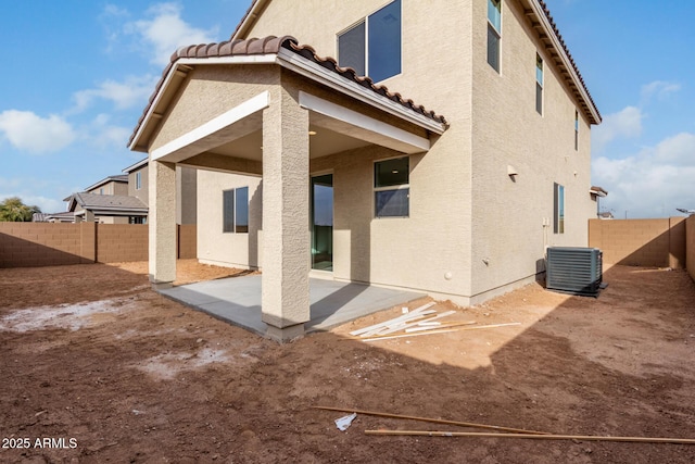 rear view of house with central AC, a fenced backyard, a patio area, and a tile roof