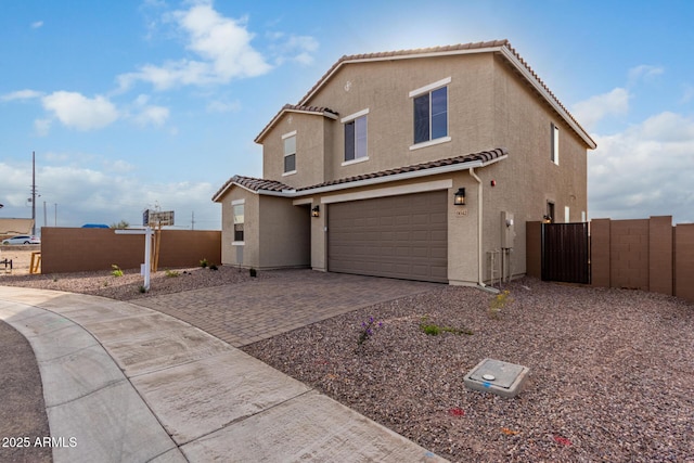 view of front of property with an attached garage, fence, a tiled roof, decorative driveway, and stucco siding