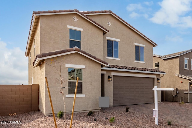 view of front of home with a garage, decorative driveway, fence, and stucco siding