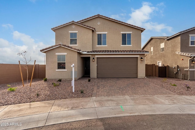 traditional home with decorative driveway, a tile roof, fence, and stucco siding