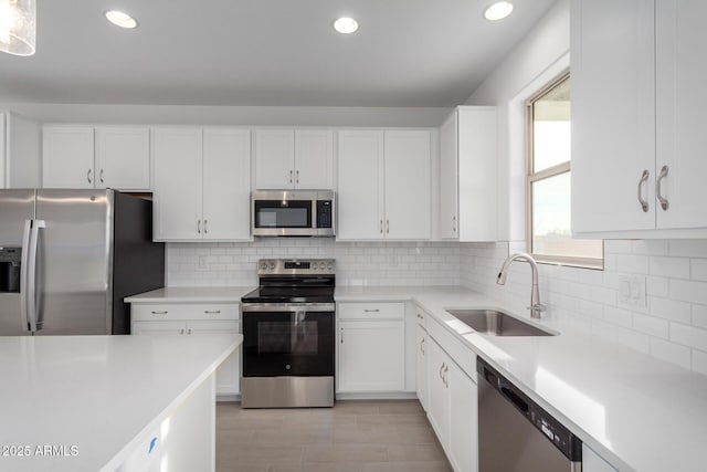 kitchen with light countertops, appliances with stainless steel finishes, a sink, and white cabinetry