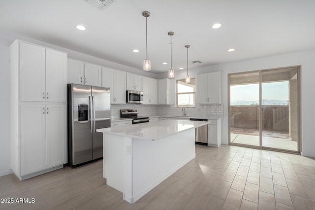 kitchen with stainless steel appliances, visible vents, backsplash, white cabinetry, and a kitchen island