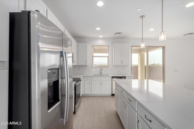 kitchen featuring a sink, visible vents, light countertops, appliances with stainless steel finishes, and decorative backsplash