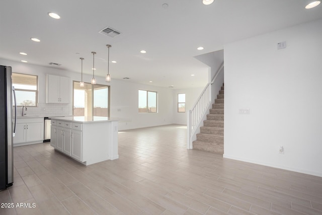 kitchen with a healthy amount of sunlight, visible vents, open floor plan, and white cabinets