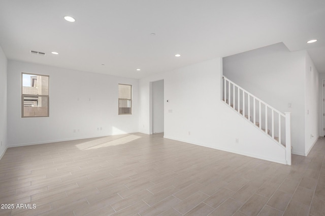 empty room featuring baseboards, visible vents, stairway, light wood-style floors, and recessed lighting