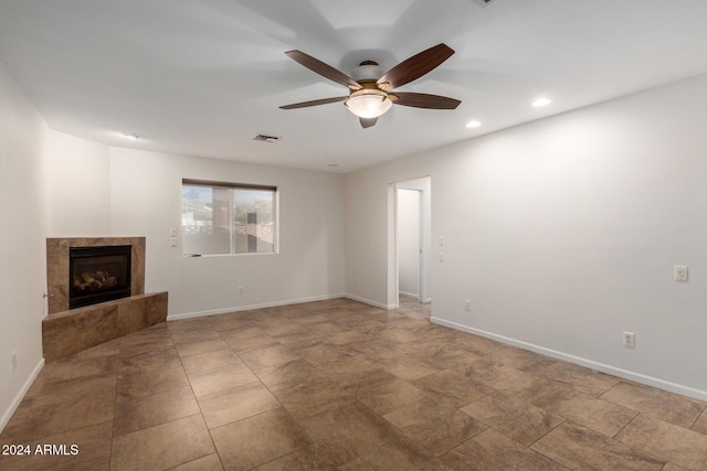 unfurnished living room with a tile fireplace and ceiling fan