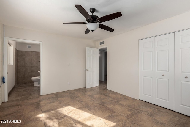 unfurnished bedroom featuring connected bathroom, ceiling fan, a closet, and tile walls