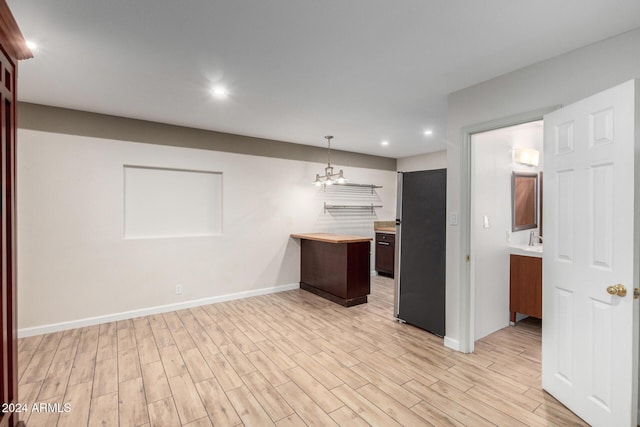 kitchen with a chandelier, sink, hanging light fixtures, and light wood-type flooring