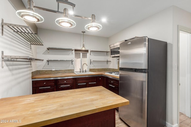 kitchen featuring decorative light fixtures, sink, butcher block counters, and stainless steel appliances