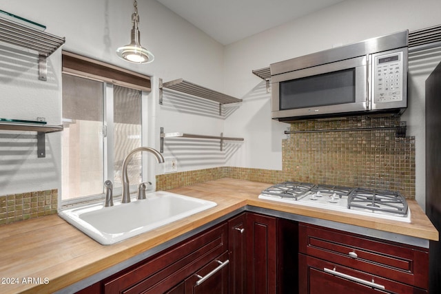 kitchen featuring pendant lighting, wood counters, sink, decorative backsplash, and gas cooktop