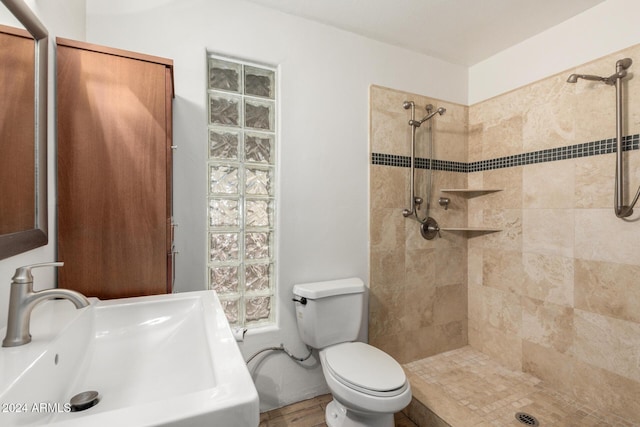 bathroom featuring toilet, sink, hardwood / wood-style floors, and tiled shower