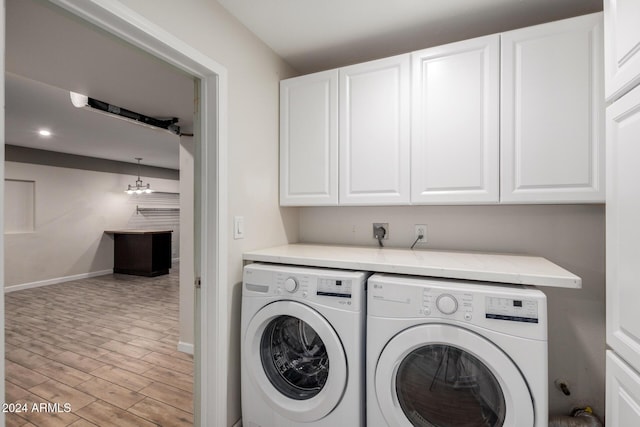 clothes washing area featuring cabinets, independent washer and dryer, and light hardwood / wood-style flooring