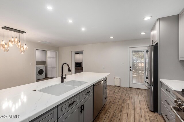 kitchen with washer / dryer, gray cabinets, appliances with stainless steel finishes, and sink