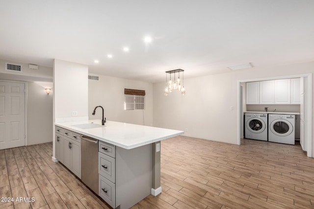 kitchen featuring dishwasher, sink, light hardwood / wood-style flooring, washing machine and dryer, and decorative light fixtures