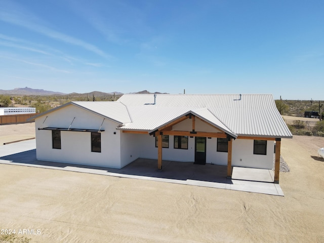 back of property featuring a mountain view and a patio