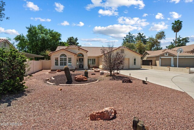 63 W Los Arboles Dr, Tempe, AZ 85284 - mediterranean / spanish-style house with an attached garage, concrete driveway, a tile roof, fence, and stucco siding