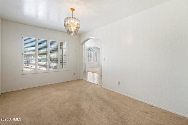63 W Los Arboles Dr, Tempe, AZ 85284 - carpeted empty room featuring arched walkways, a notable chandelier, and baseboards