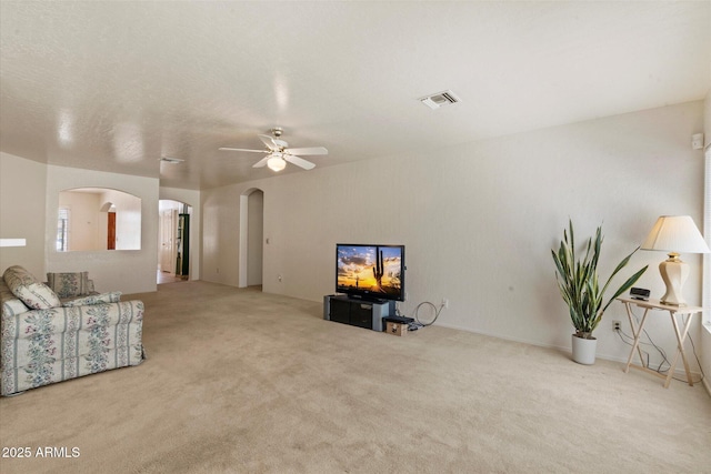 63 W Los Arboles Dr, Tempe, AZ 85284 - unfurnished living room with arched walkways, carpet flooring, visible vents, and a ceiling fan