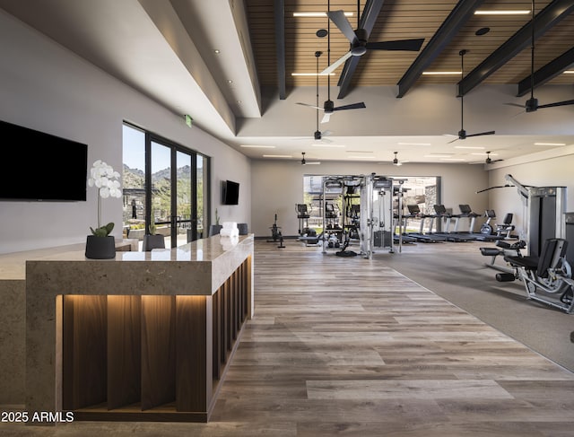 exercise room with wood ceiling, wood-type flooring, and a high ceiling