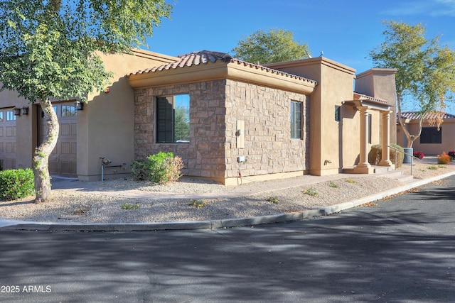 view of home's exterior featuring stone siding, stucco siding, and a tile roof