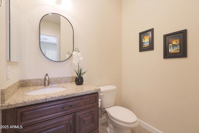 bathroom with baseboards, toilet, and vanity