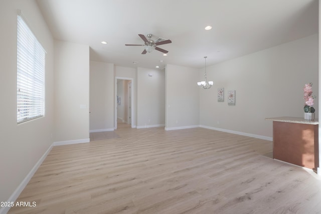 interior space with light wood finished floors, recessed lighting, ceiling fan with notable chandelier, and baseboards