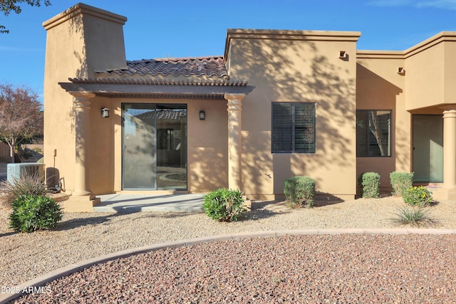 rear view of property featuring central air condition unit, stucco siding, and a tiled roof