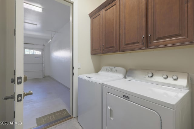 laundry area featuring washer and clothes dryer, cabinet space, and a garage