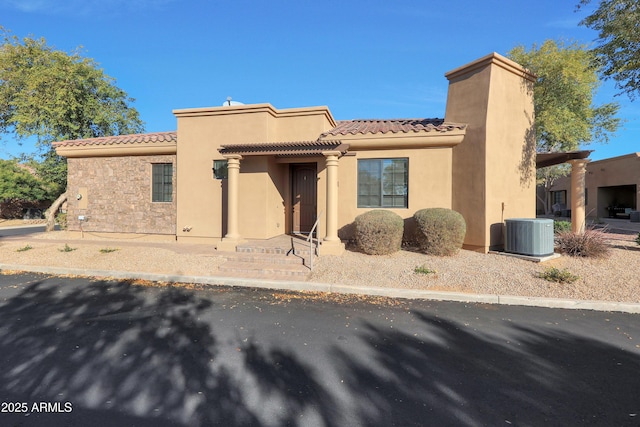 view of front of property with cooling unit, stone siding, stucco siding, and a tile roof