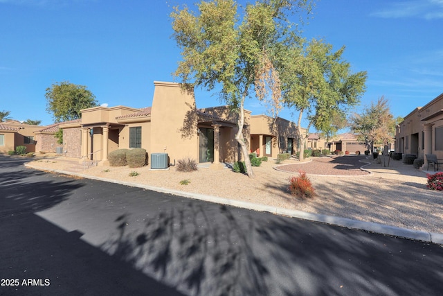 view of front of property with a tile roof, cooling unit, a residential view, and stucco siding