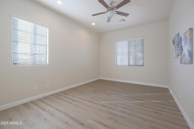 spare room with light wood-style flooring, a ceiling fan, visible vents, and baseboards