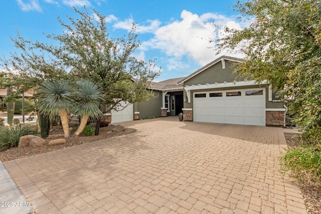 view of front of property featuring an attached garage, stone siding, decorative driveway, and stucco siding